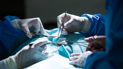 Surgeons perform a delicate operation using medical tools in a sterile operating room.