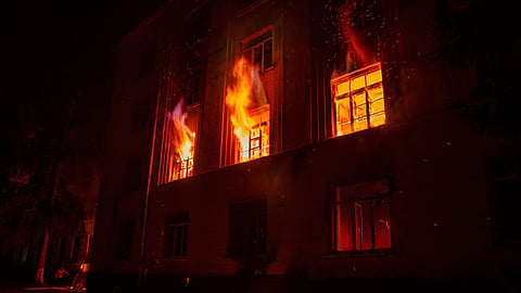 A building burns with intense flames and sparks, lighting up the night sky.