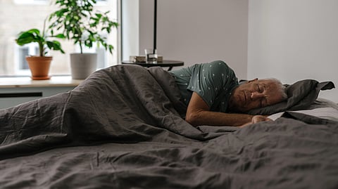 An older man peacefully sleeping in bed.