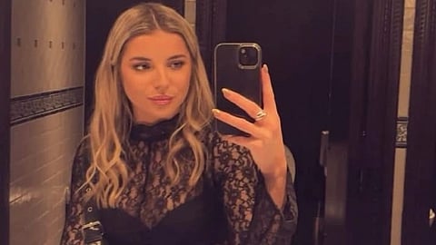 Ellie in a black top, holding a phone.