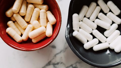 Two bowls filled with various pills placed on a polished marble surface.