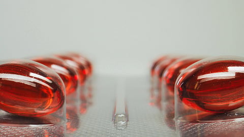 Close-up of a blister pack containing shiny red capsules arranged in two neat rows.