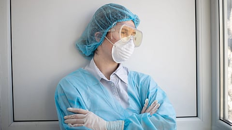 A woman wearing a surgical mask and gloves for health and safety.