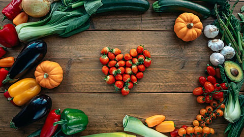A heart-shaped arrangement of various colorful vegetables and fruits.