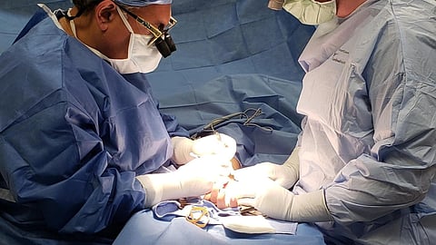 Two surgeons perform surgery on a patient in an operating room