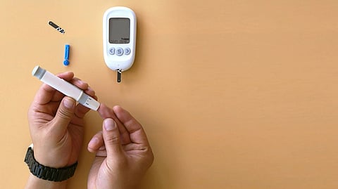 Person using lancet pen and glucometer for blood glucose monitoring