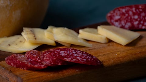 Close-up shot shows a wooden board with several slices of salami and cheese.