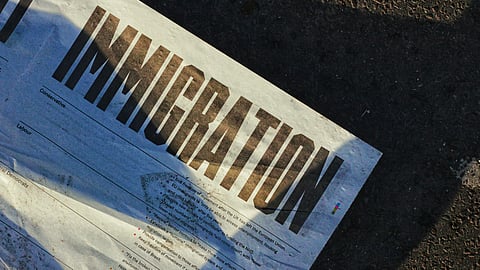 An open newspaper on the ground showing an article about immigration.