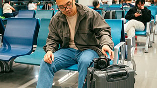 A man sits at an airport with his luggage.