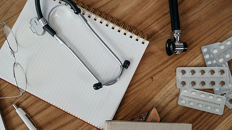 A notepad with stethoscope and meds.