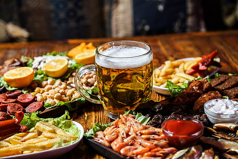 Front view of beer snacks with lemon wedges on a stand with a glass of beer