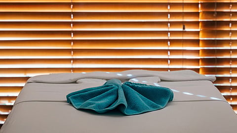 A massage table with a folded towel in a calm, relaxing spa setting.