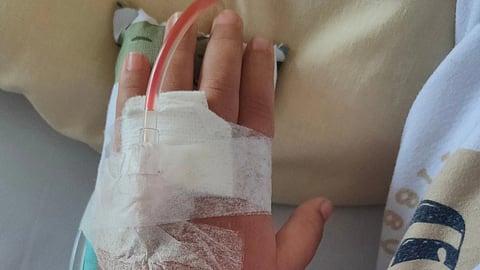 A child's hand with canula and bandage.