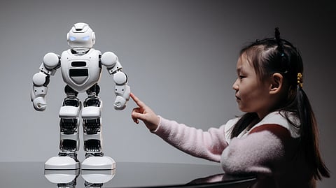 A young girl excitedly points at a colorful robot.