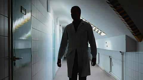 a man in a white coat walking down a hallway