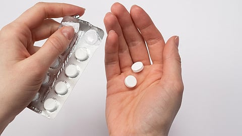 A woman holds two tablets in her hand.