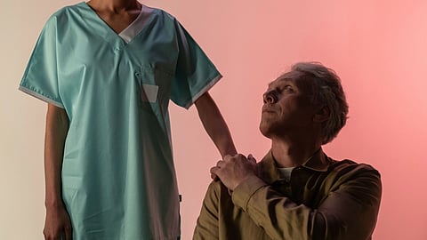 A healthcare worker gently comforts an elderly man.
