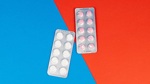Two packs of pills on a blue and red split background.