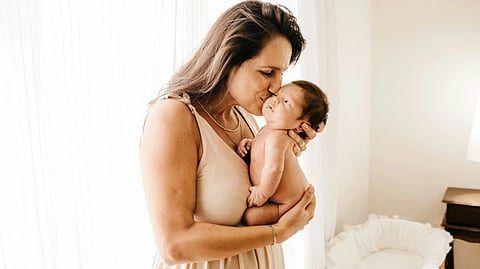 A mother gently cradles her newborn in a cozy, peaceful room.