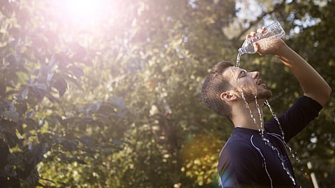 An athlete pours water over his face and head to cool down.