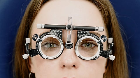 A woman wears trial frames during an eye exam.