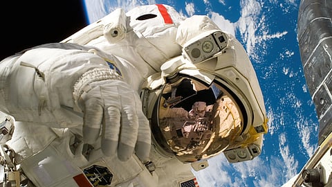 An astronaut performs a spacewalk above Earth.