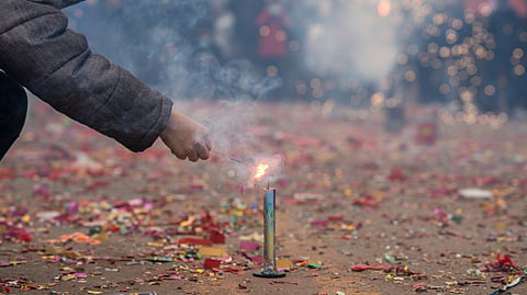 A person lights a firework as a crowd watches nearby.