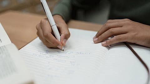 Someone writing an ecamination, holding a pen.