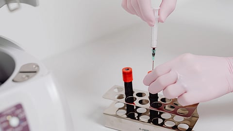 someone putting blood in test tubes through a syringe.