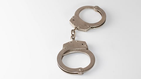 Silver handcuffs on a white surface.
