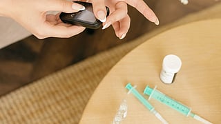 Person holding a blood glucose meter while sitting on a couch.