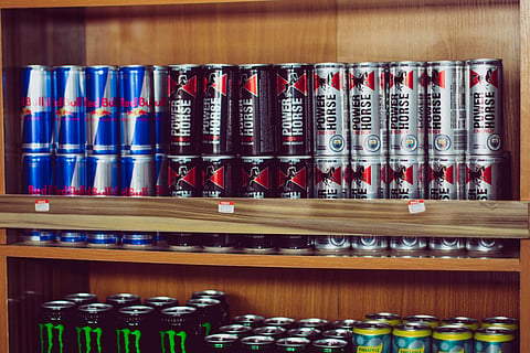 Red Bull and other energy drink cans displayed together on a retail shelf.