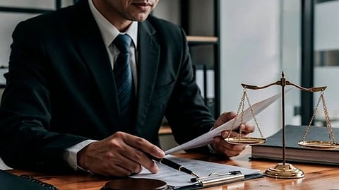 A person reviews legal documents at a desk with a gavel and scales of justice.