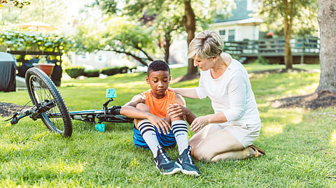 A woman comforts a boy after a bicycle fall.