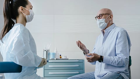 An older man talks with a doctor in a clinic.