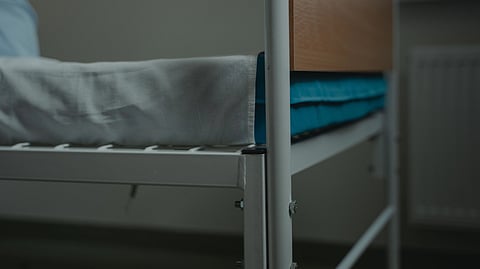 A hospital bed with white and blue sheets.