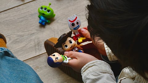 A child plays with Toy Story figures on the floor.