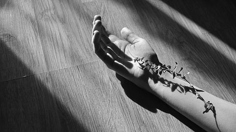 A black-and-white image of a person's hand resting on the floor.