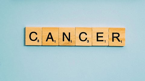 Wooden tiles spell out "CANCER" on a blue background.
