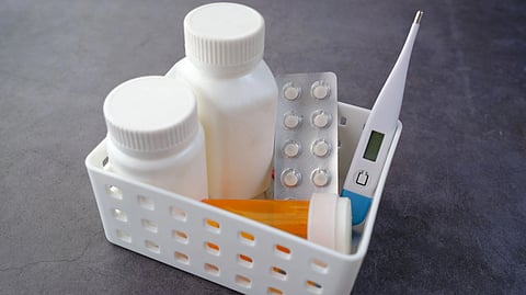 A basket with medicines, pills, and a thermometer.