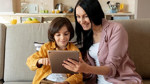 A woman and a boy use a tablet together at home.