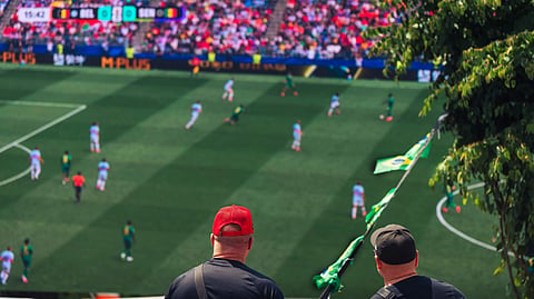 A man in a red hat watches a soccer match.