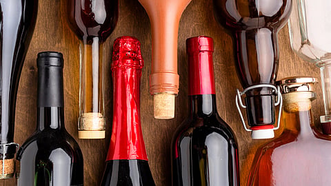 A variety of wine bottles and corks on a wooden table.