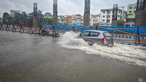 A car drives through a flooded street after heavy rain.