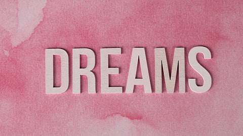 The word "Dreams" on a soft pink background.
