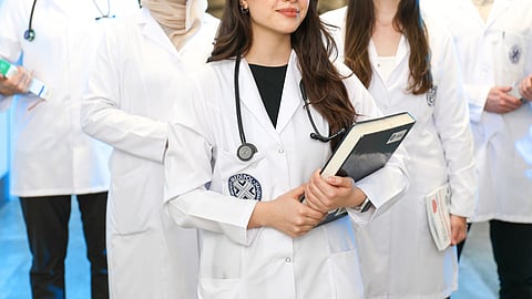 Doctors in white coats discussing patient care in a hospital hallway.