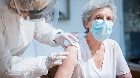 A doctor gives a woman a vaccine in a clinic.