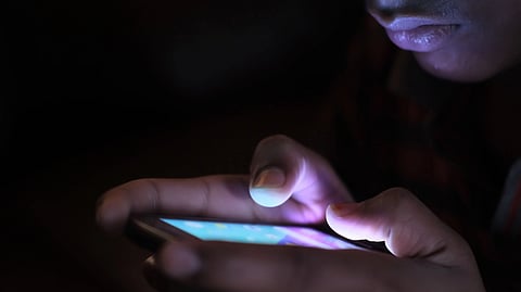 A person uses a smartphone in a dark room.