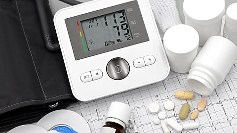 A blood pressure monitor with medicines on a table.