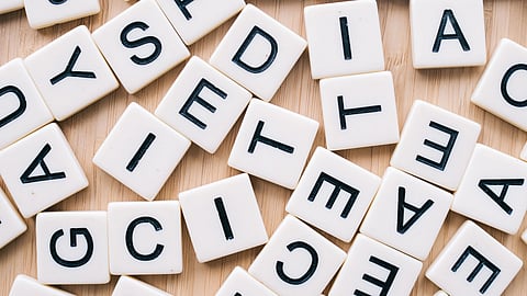 Scrabble letter tiles scattered on a wooden table.